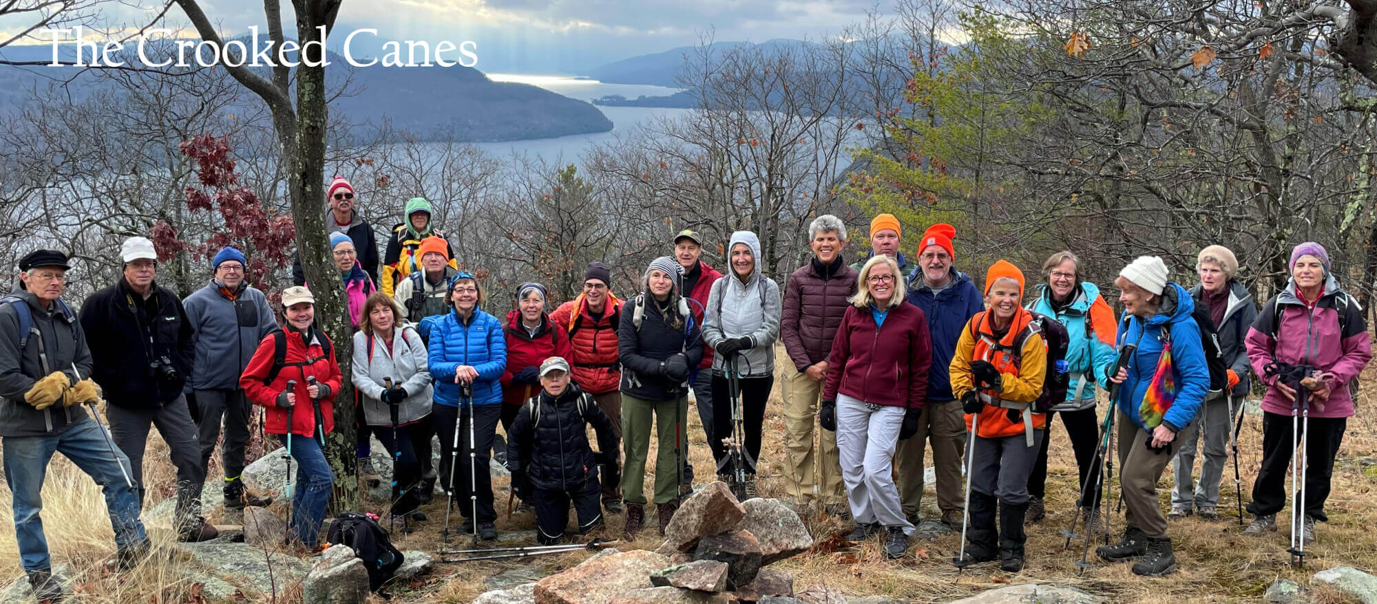 Crooked Canes hiking group, active hiking, paddling, skiing and biking enthusiasts, are shown on an Adirondacks mountain with a view of Lake George.
